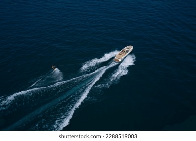 Aerial view of a man wakeboarding on the water. Water skiing on the water behind the boat. - Powered by Shutterstock