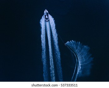 Aerial view of man wakeboarding on lake. Water skiing on lake behind a motorboat. - Powered by Shutterstock