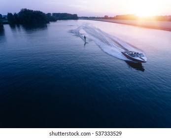 Aerial view of man wakeboarding on lake at sunset. Water skiing on lake behind a boat.