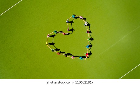 Aerial View Of Many People Making Heart Shape On Green Field. Top View.