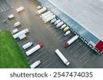 Aerial view of many trucks at the loading docks of a large distribution warehouse.