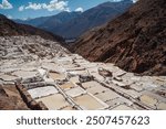 Aerial view of the Maras Salt Mines in the Sacred Valley of the Incas, Peru, showcasing a stunning network of terraced salt evaporation ponds nestled in the Andean mountains.