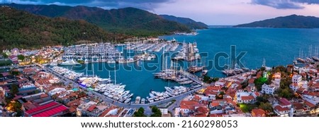 Aerial view of Marmaris harbor with yacht and sailboat with evening lighting. Colorful landscape of the night Turkish city. Beautiful sky at sunset