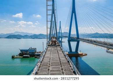 Aerial view of a massive cable-stayed bridge deck under construction showing concrete structure and steel cables over the ocean, Ningbo, China