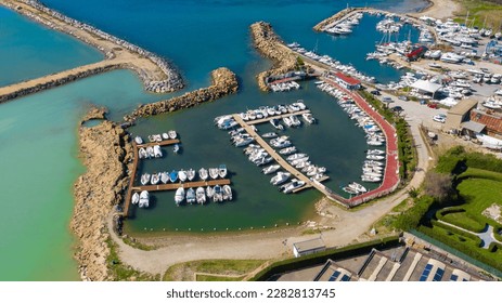 Aerial view of Mattonara and Buca di Nerone, an archaeological area located in Civitavecchia near Rome, Italy. The area has been affected by marine erosion. There is a marina with many boats. - Shutterstock ID 2282813745
