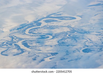 Aerial view of a meandering river in the tundra. The curves of the river bed in the plain. Snow-covered tundra in the Arctic. Mayn River, Chukotka, Siberia, Far East of Russia. Great for backgrounds. - Powered by Shutterstock