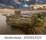 Aerial view of medieval Anglo Norman Carrickfergus castle with large rectangular keep dramatic sunset sky