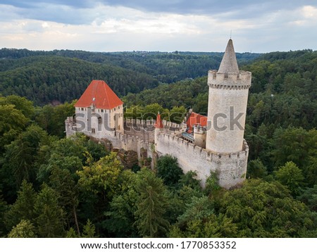 Aerial view of a medieval castle Kokorin. Fortified stone palace with a tower and a wall, red roofs, standing on a hill covered by trees.  Castles in the Central Bohemian Region, Czech republic.