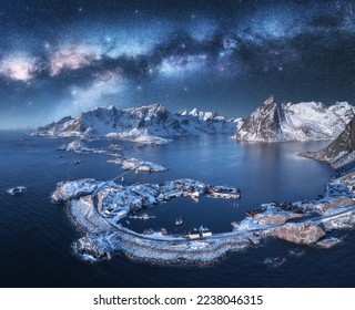 Aerial view of Milky Way arch, sea, village and snow covered mountains in winter at night. Lofoten Islands, Norway. Arctic landscape with starry sky, road, rorbu, houses, milky way, snowy rocks. Space - Powered by Shutterstock