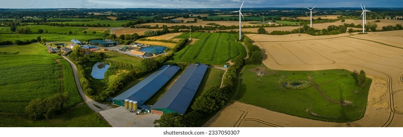 Aerial view of modern agriculture farm with agricultural fields with corn, biogas plant, wind turbines, photovoltaic panels on the roofs of barns. High-tech farming and renewable resources concept. - Powered by Shutterstock