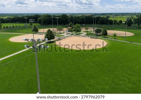 Aerial view of a modern baseball complex with multiple diamond fields, manicured grass outfields, lighted poles, and recreational facilities set in a sprawling park in Elgin, Illinois.