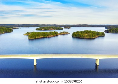 Aerial View Of Modern Bridge With Cars Across Blue Lake Saimaa At Summer Sunset Time. Beautiful Sky With Clouds. Finland