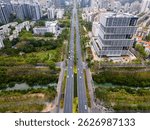 Aerial view of a modern city with a central avenue, high-rise buildings, green parks, and a canal. Urban planning and infrastructure in a vibrant metropolitan area