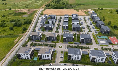 Aerial view of a modern residential complex with multiple buildings, green spaces, and parking areas. Solar panels are visible on rooftops, and a basketball court is nearby.  - Powered by Shutterstock