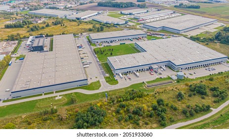 Aerial View Of Modern Storage Warehouse With Solar Panels On The Roof. Logistics Center In Industrial City Zone From Drone View. Background Texture Concept.