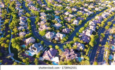 Aerial view of modern suburban neighborhood from above with green landscapes and trees, pools, and houses, in Las Vegas, Nevada
