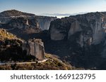 Aerial view of monastery Rousanou and breathtaking picturesque valley and landmark canyon of Meteora at sunset, Kalambaka, Greece, shadows, twisted road, bridge