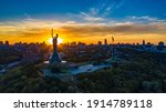 Aerial view to the Motherland statue in the Kiev while  summer sunset. The well-known landmarks in Kyiv. Historical monument of Soviet union. Beautiful city Kiev while sunset. Ukraine flag