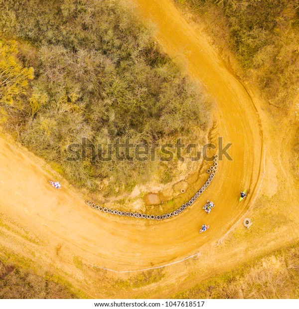 Aerial view of motocross bikes and\
quad bike in racetrack. Outdoor motor sport from drone\
view.