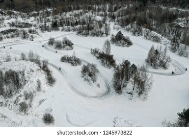 Aerial View To Motorcycle Rider On Snowy Motocross Track. Mx Rider On Snow. Motocross Rider On Bike, Motocross Winter Season Race. Drone View Racer Motorcycle Rides On Motocross Snowy Track In Winter.