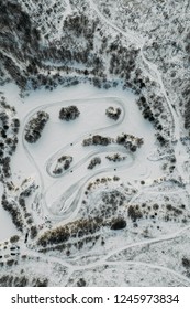 Aerial View To Motorcycle Rider On Snowy Motocross Track. Mx Rider On Snow. Motocross Rider On Bike, Motocross Winter Season Race. Drone View Racer Motorcycle Rides On Motocross Snowy Track In Winter.