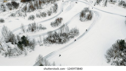 Aerial View To Motorcycle Rider On Snowy Motocross Track. Mx Rider On Snow. Motocross Rider On Bike, Motocross Winter Season Race. Drone View Racer Motorcycle Rides On Motocross Snowy Track In Winter.