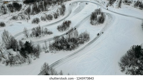 Aerial View To Motorcycle Rider On Snowy Motocross Track. Mx Rider On Snow. Motocross Rider On Bike, Motocross Winter Season Race. Drone View Racer Motorcycle Rides On Motocross Snowy Track In Winter.