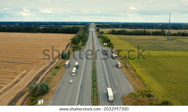 Aerial view of a motorway in summer on a cloudy day.\
Aerial view of a suburb road with trucks. Drone  above a highway\
with driving cars. 