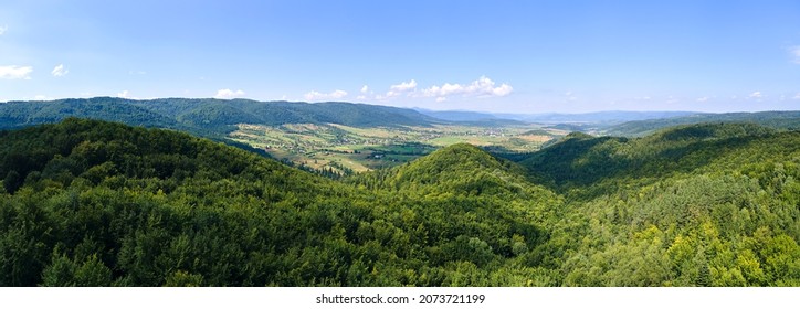Aerial view of mountain hills covered with dense green lush woods on bright summer day. - Shutterstock ID 2073721199