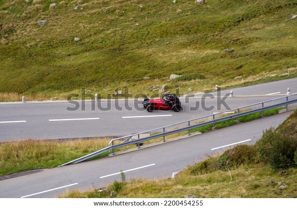 Aerial\
view of mountain pass road and caterham 7 sports car at Swiss\
mountain pass Oberalppass on a late summer day. Photo taken\
September 5th, 2022, Oberalp Pass,\
Switzerland.