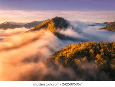 Aerial view of mountain peak in low clouds at sunrise in autumn. Top drone view of hills with red and orange trees in fog, colorful sky in fall. Slovenia. Nature. Mountain valley. Autumn forest. Alps - Powered by Shutterstock