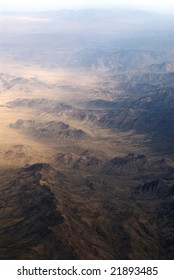 An aerial view of a mountain range from inside an airplabe.