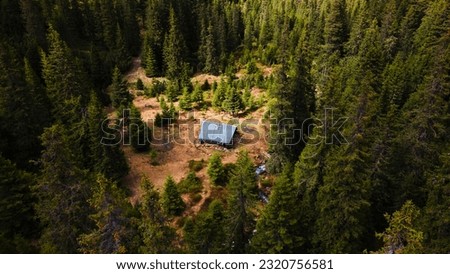 Aerial view of a mountain refuge hut, deep in the Carpathian Mountains. Cabin in the middle of the woods seen from above.