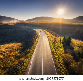 Aerial View Of Mountain Road In Forest At Sunset In Autumn. Top View From Drone Of Road In Woods. Beautiful Landscape With Roadway In Hills, Pine Trees, Green Meadows, Golden Sunlight In Fall. Travel