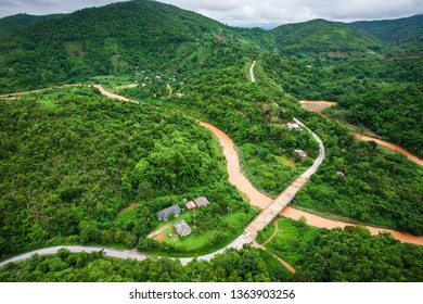 Aerial view of mountain road and river in rainy season, a village road and river is going overflow, rural scene in North Thailand.
