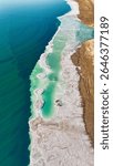 Aerial view of mushroom-shaped salt formations in the Dead Sea shoreline. Unique natural sculptures rising from vivid blue water in a surreal desert landscape. In Vertical Format.