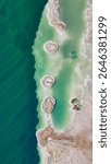 Aerial view of mushroom-shaped salt formations in the Dead Sea shoreline. Unique natural sculptures rising from vivid blue water in a surreal desert landscape.