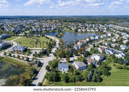 Aerial view of a neighborhood housing development in suburban Chicago during summer with pond and play area.