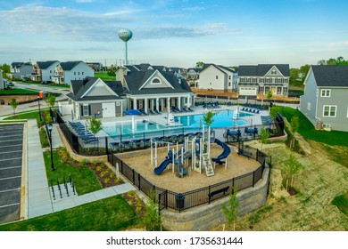 Aerial View Of New Construction Community Pool At A Club House With Blue Beach Chairs And Playground In The East Coast USA