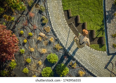 Aerial View Of New Residential Garden Developing By Caucasian Landscaping Worker. Planting Flowers, Decorative Trees And Natural Grass Installation