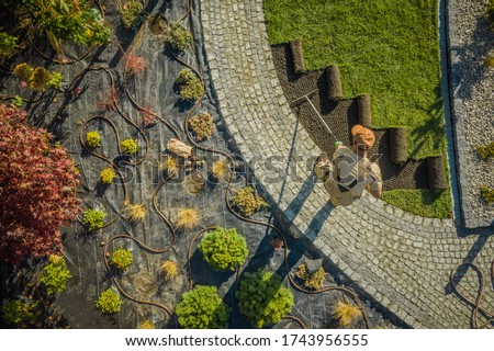 Aerial View of New Residential Garden Developing by Caucasian Landscaping Worker. Planting Flowers, Decorative Trees and Natural Grass Installation