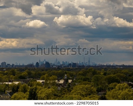 An aerial view of the New York City skyline on a cloudy day, shot with a drone camera with a Long Island, New York residential neighborhood in the foreground.