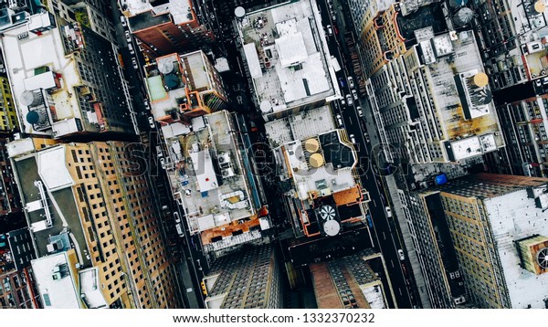 Aerial view of New York downtown building roofs\
with water towers. Bird\'s eye view from helicopter of cityscape\
metropolis infrastructure, traffic cars moving on city streets and\
district avenues