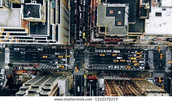 Aerial view of New York downtown building roofs.\
Bird\'s eye view from helicopter of cityscape metropolis\
infrastructure, traffic cars, yellow cabs moving on city streets\
and crossing district\
avenues