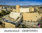 Aerial view of newly restored Elda castle in Valencia province, with newly restore white stone curtain wall, square and round tower in the middle of the Spanish town with blue sky