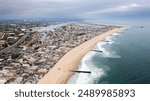 Aerial View of Newport Beach, California, Showing a Sandy Shoreline with Waves Crashing Incessantly into the Partially Submerged Jetties