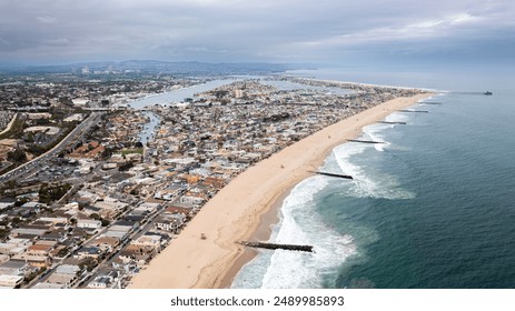 Aerial View of Newport Beach, California, Showing a Sandy Shoreline with Waves Crashing Incessantly into the Partially Submerged Jetties - Powered by Shutterstock