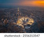 Aerial view at night of the illuminated Grand Mosque and Abraj Al-Bait Clock Tower in Mecca, showcasing the city’s vibrant glow as lights shimmer across the holy site