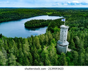 Aerial view of observation tower with Finnish flag among blue lakes and green forests in summer Finland. Aulanko Observation Tower, Hameenlinna, Finland