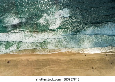 Aerial view of ocean beach. Sand beach and sea view from above. Beach aerial view of ocean water and sand shore. Aerial shot of beach emphasizing the scale of people and nature